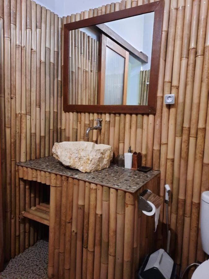 a bathroom with a sink and a mirror on a bamboo wall at Kirana Homestay in Amed