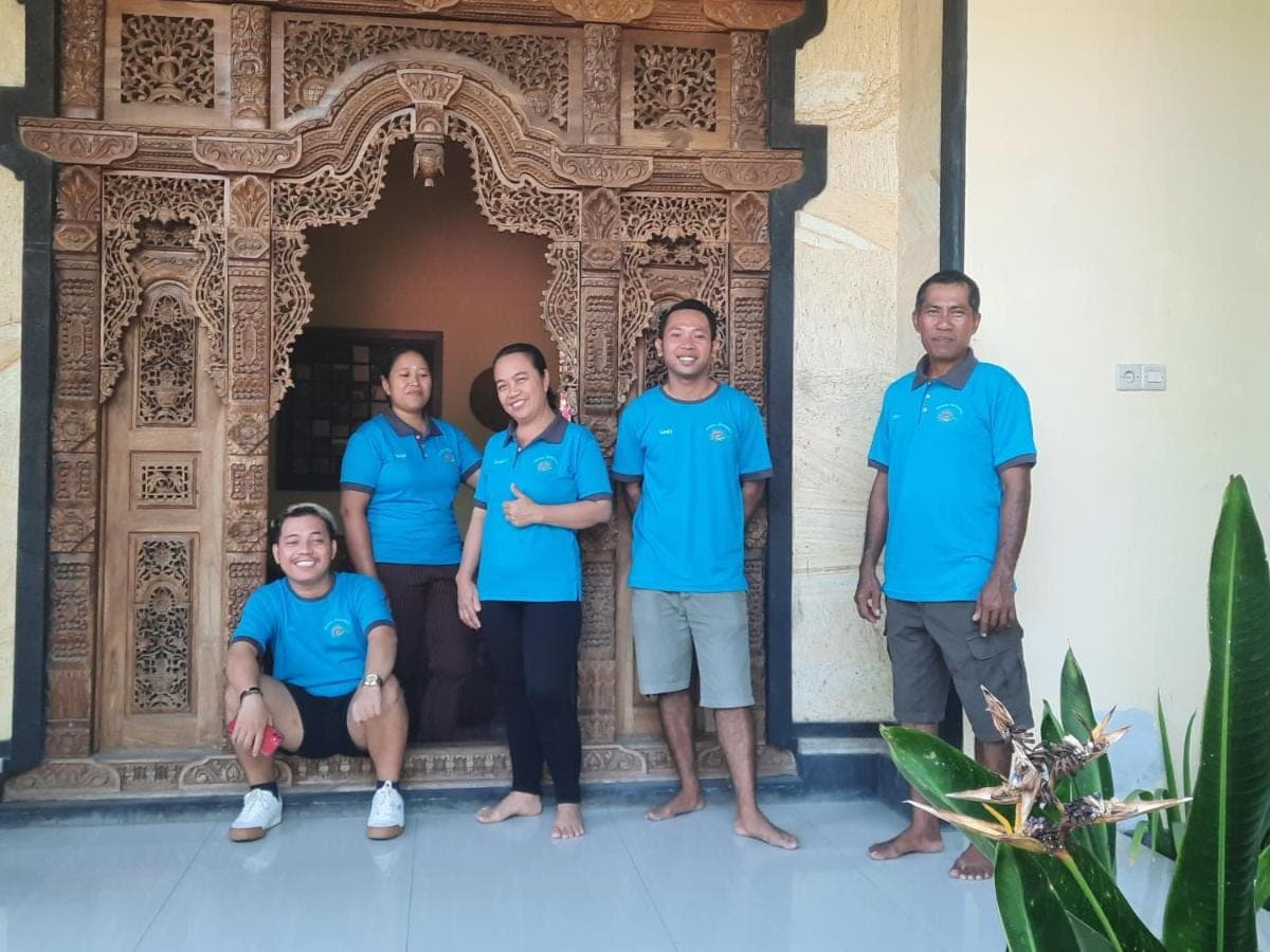 a group of people wearing blue shirts standing in front of a building at Kirana Homestay in Amed