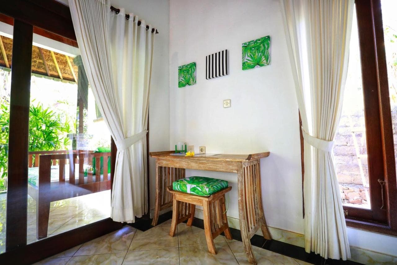 a small table and stool in a room with a window at Kirana Homestay in Amed