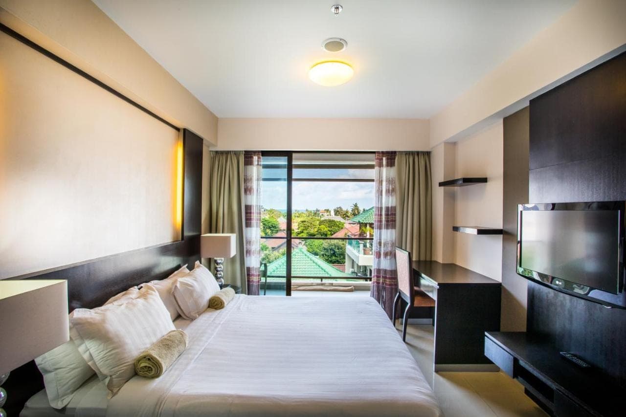 a hotel room with a bed and a television at Kuta Reef Apartments in Kuta