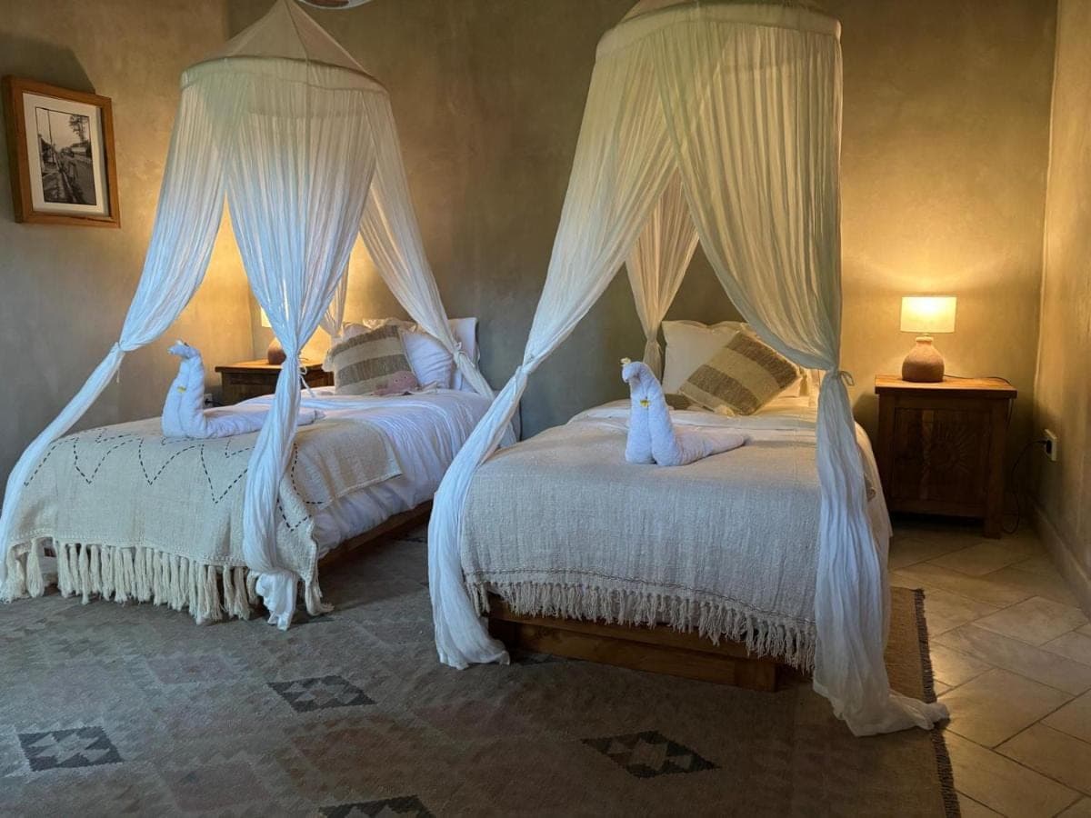 two beds in a bedroom with white drapes at First Light Villa at Lipah Beach, Amed in Amed