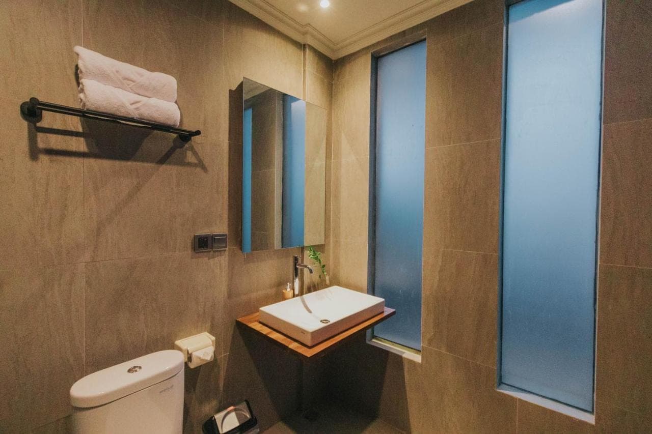 a bathroom with a sink and a toilet and a window at Tubobi House in Ubud
