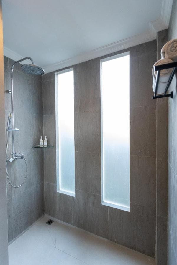 a bathroom with a shower and two windows at Tubobi House in Ubud
