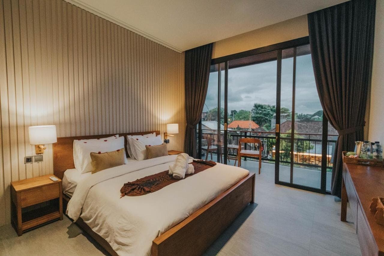 a bedroom with a large bed and a balcony at Tubobi House in Ubud