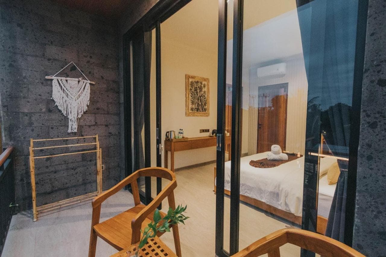 a bedroom with a bed and a glass door at Tubobi House in Ubud