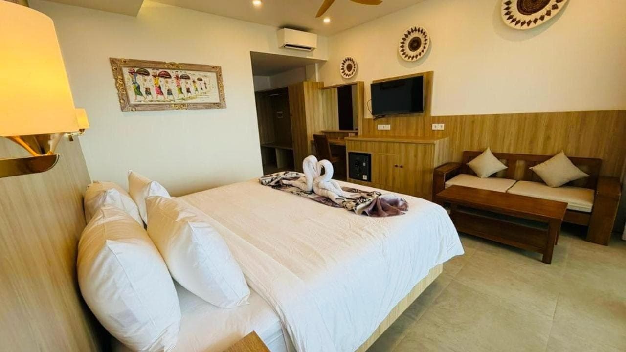 a bedroom with a bed and a couch and a television at Solaluna Beach Homestay in Amed