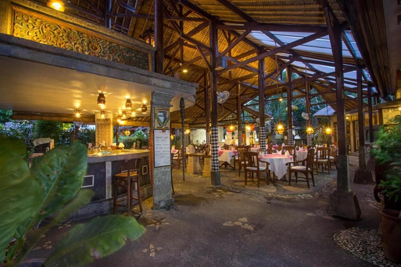 a restaurant with tables and chairs in a building at Tamukami Hotel in Sanur