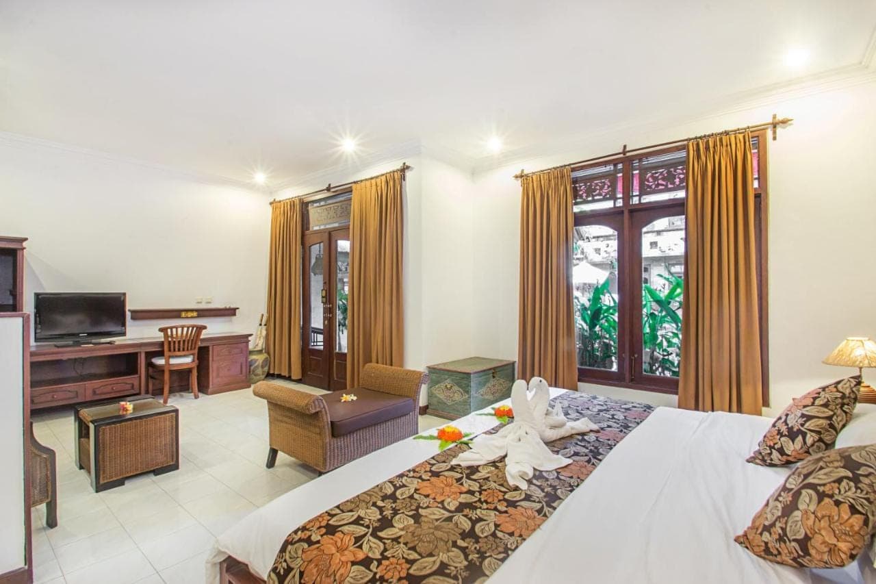a hotel room with a large bed and a television at Tamukami Hotel in Sanur
