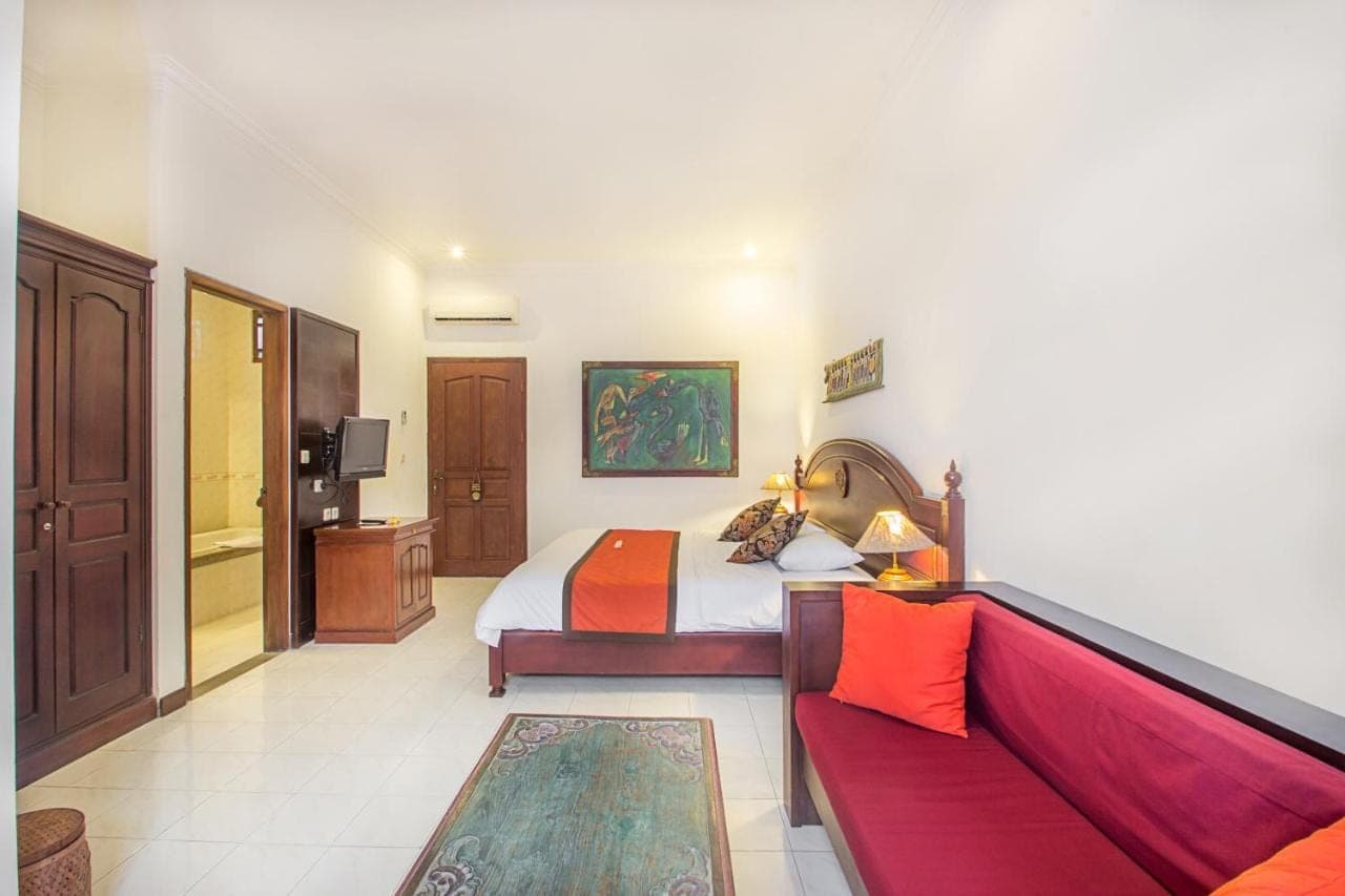a hotel room with a bed and a couch at Tamukami Hotel in Sanur