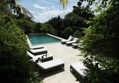 a group of lounge chairs next to a swimming pool at Baliku Dive Resort in Amed