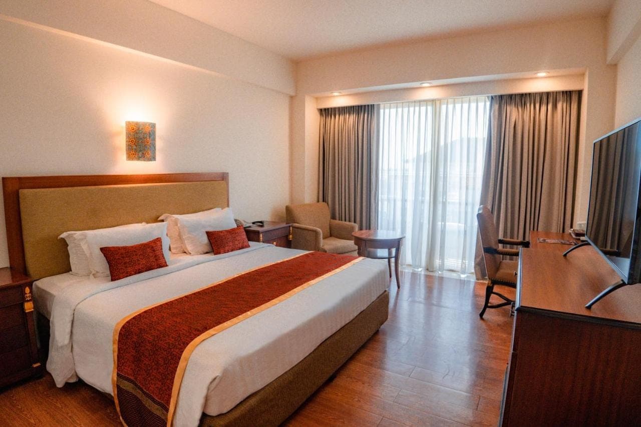 a hotel room with a bed and a flat screen tv at Kuta Paradiso Hotel in Kuta