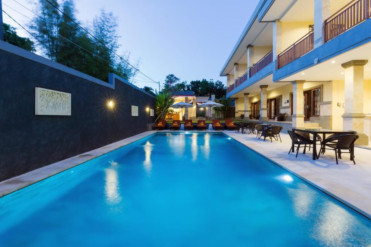 a swimming pool with tables and chairs next to a building at Kubu Petitenget Suite Seminyak in Seminyak