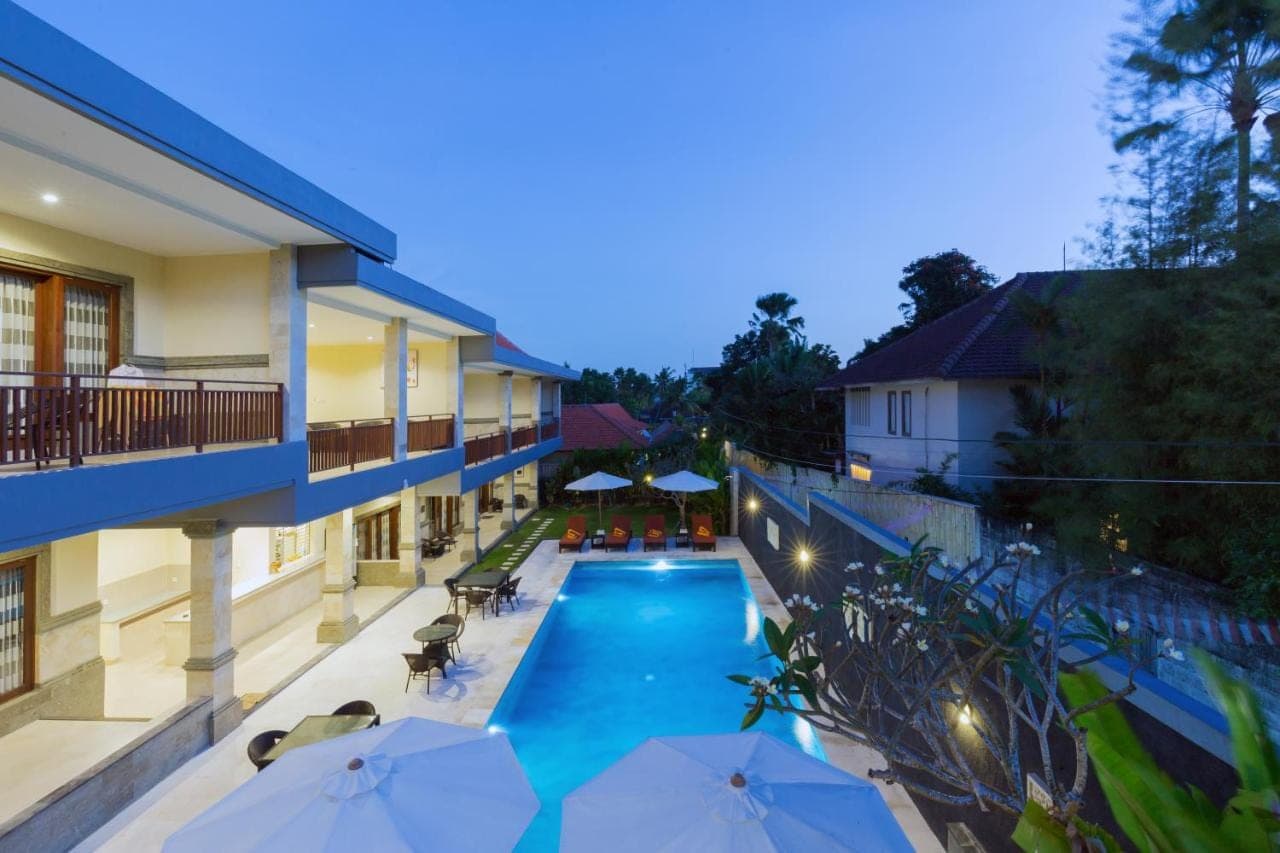 a swimming pool with umbrellas next to a building at Kubu Petitenget Suite Seminyak in Seminyak