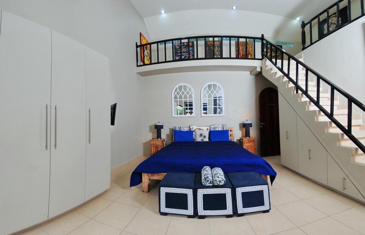 a bedroom with a bed and a spiral staircase at Villa Costa Sanur in Sanur