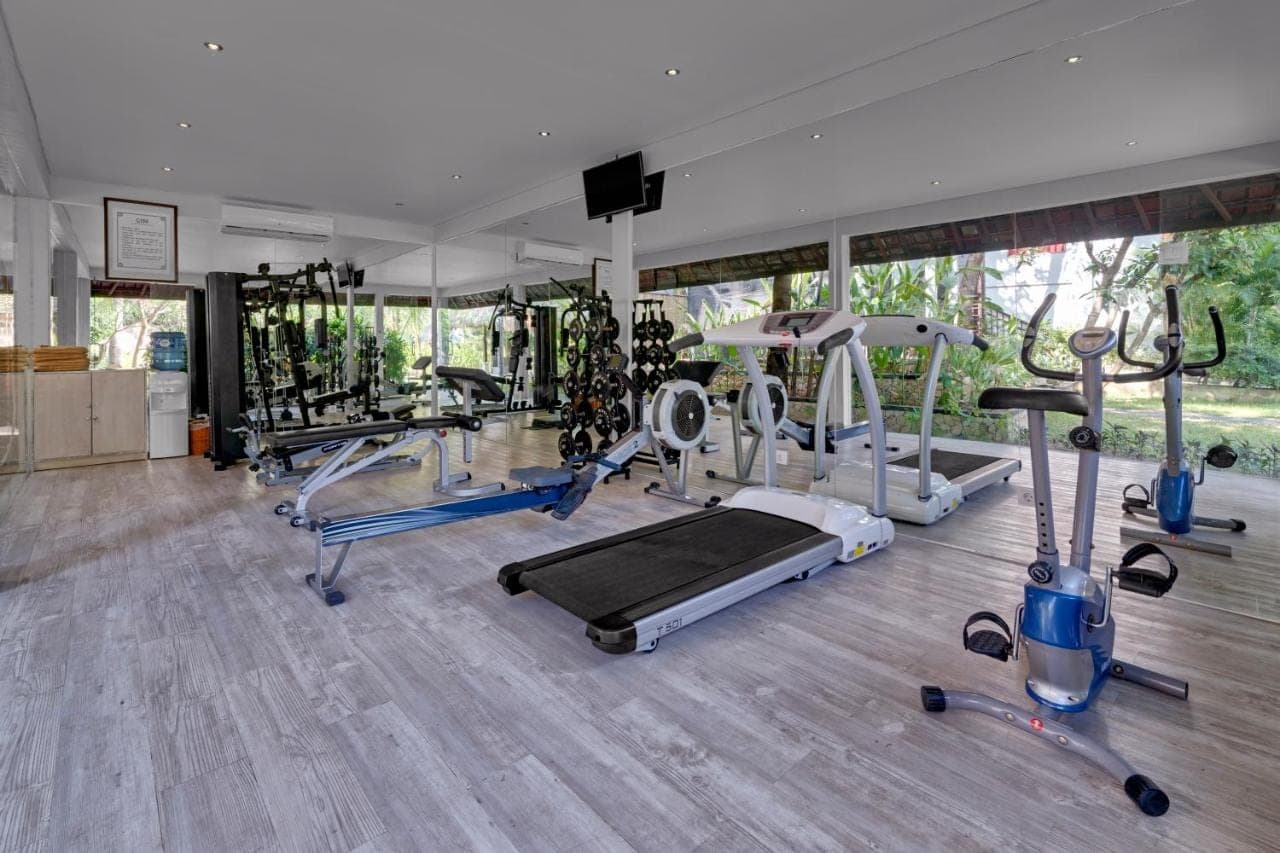a gym with several treadmills and machines in it at Bali Garden Beach Resort in Kuta