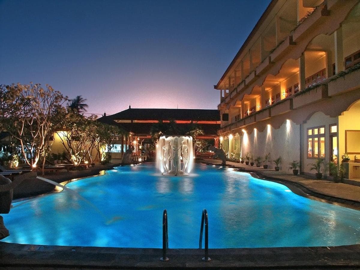 a swimming pool with a fountain in front of a building at Febri's Hotel &amp; Spa in Kuta