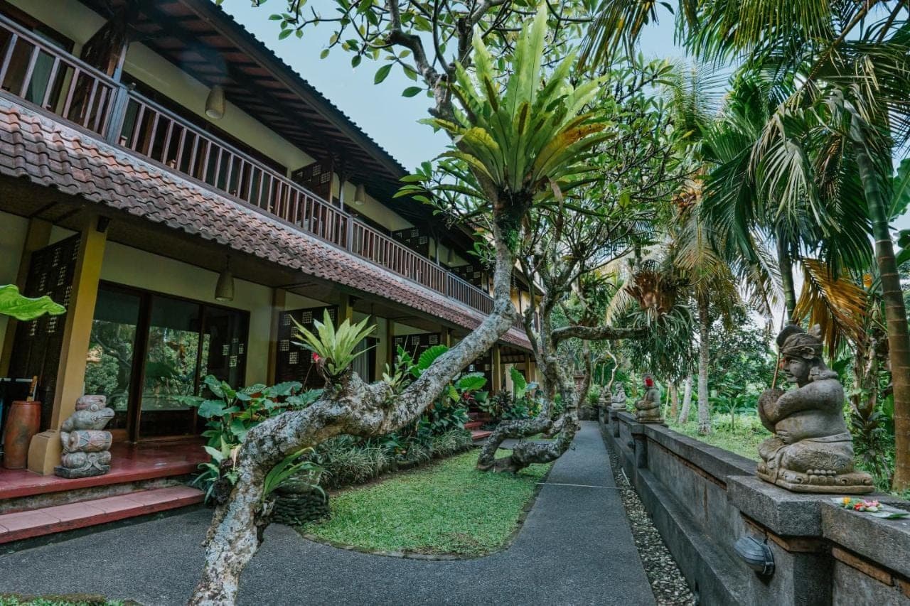 a courtyard of a house with palm trees and a statue at Jati Home Stay in Ubud