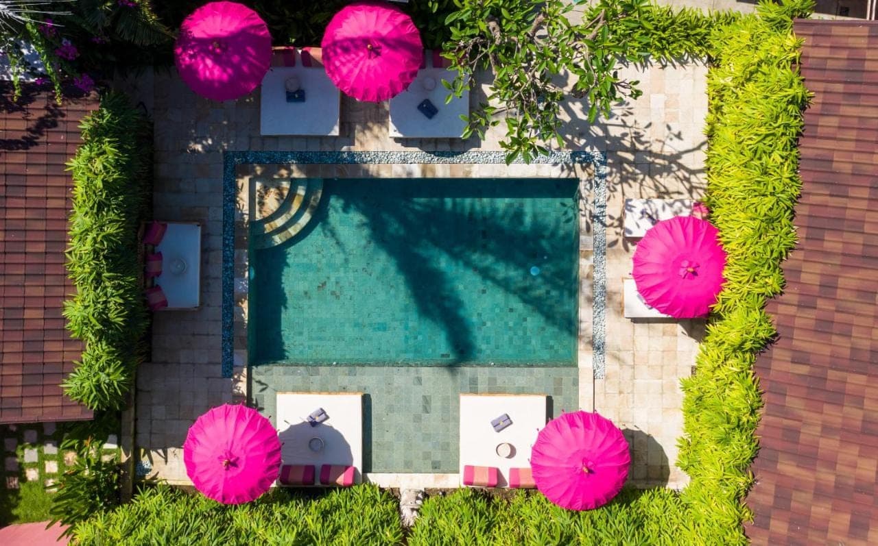 an overhead view of a swimming pool with pink umbrellas at PinkPrivate Sanur - for Cool Adults Only in Sanur