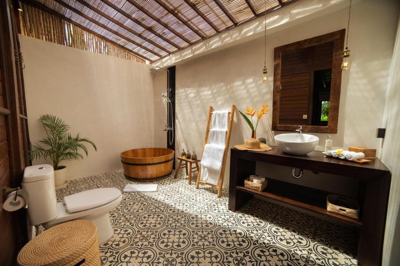 a bathroom with a toilet and a sink and a tub at Kayu Village in Canggu