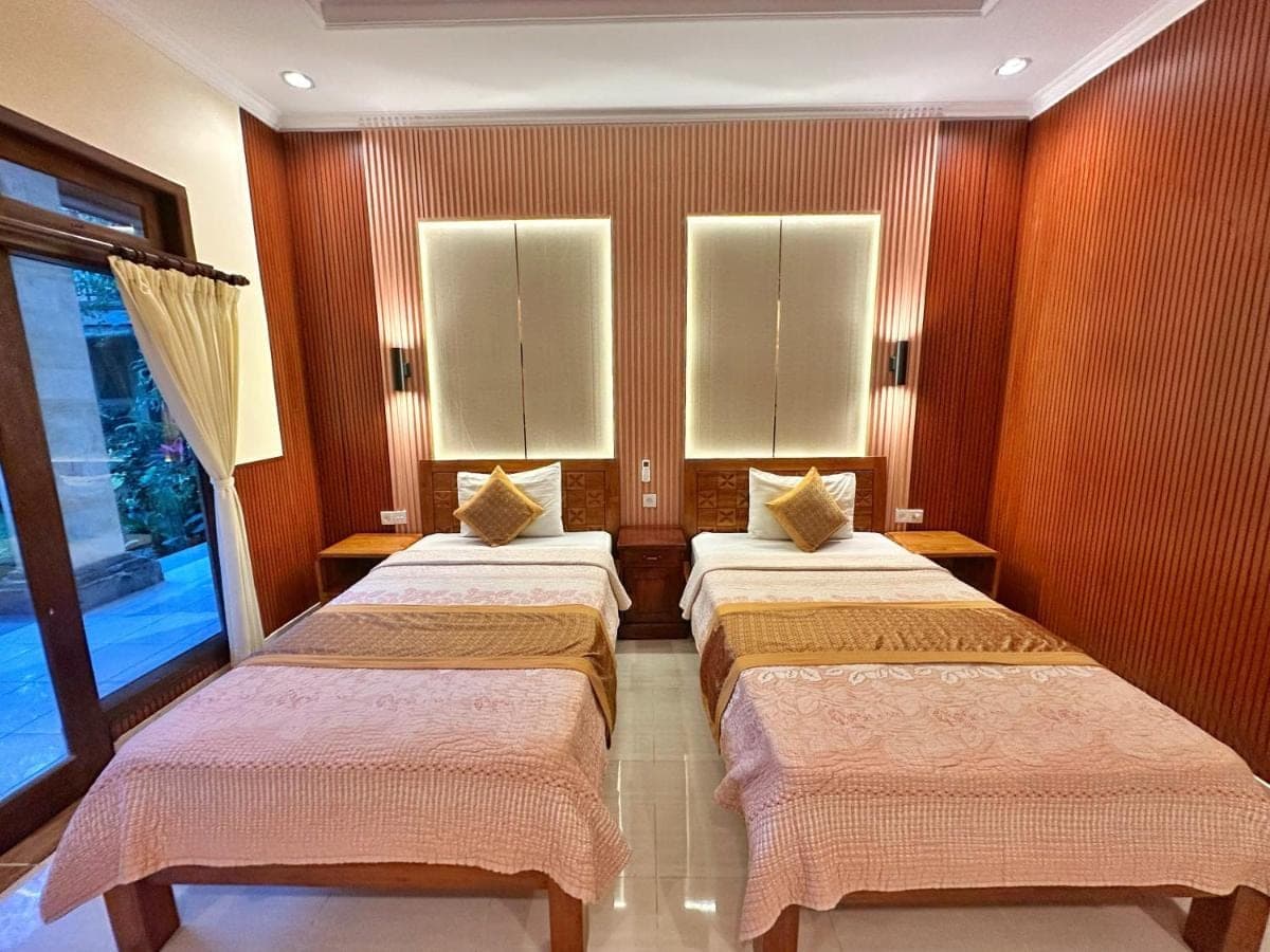 two beds in a room with two windows at Frangipani Bungalow in Ubud