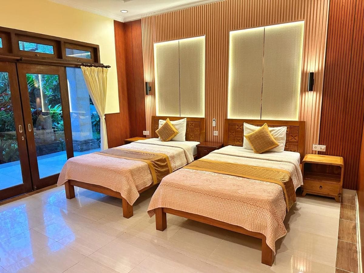 a room with two beds in a room at Frangipani Bungalow in Ubud
