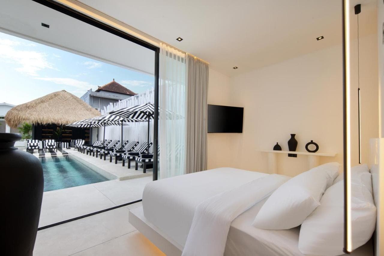 a bedroom with a bed and a view of a pool at The Den Canggu in Canggu