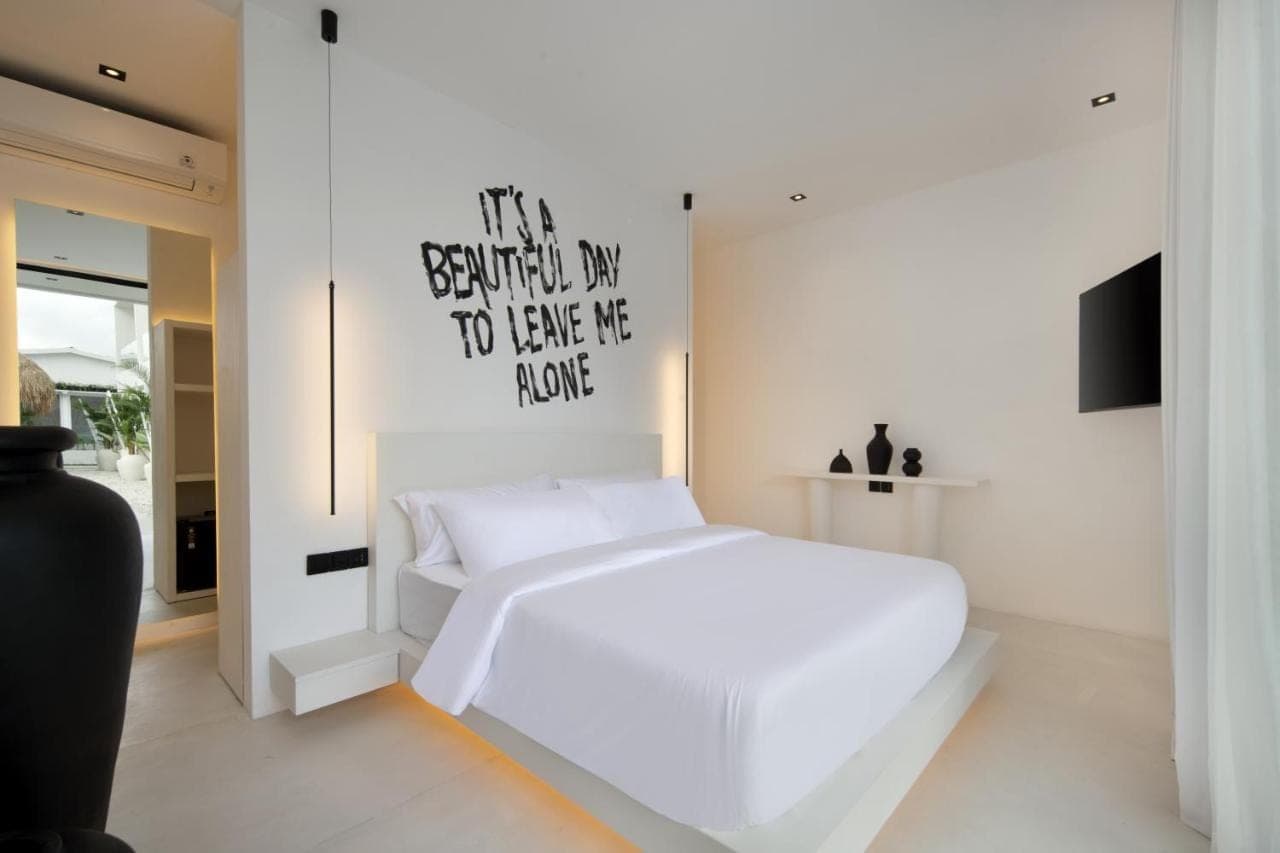 a bedroom with a white bed with a sign on the wall at The Den Canggu in Canggu