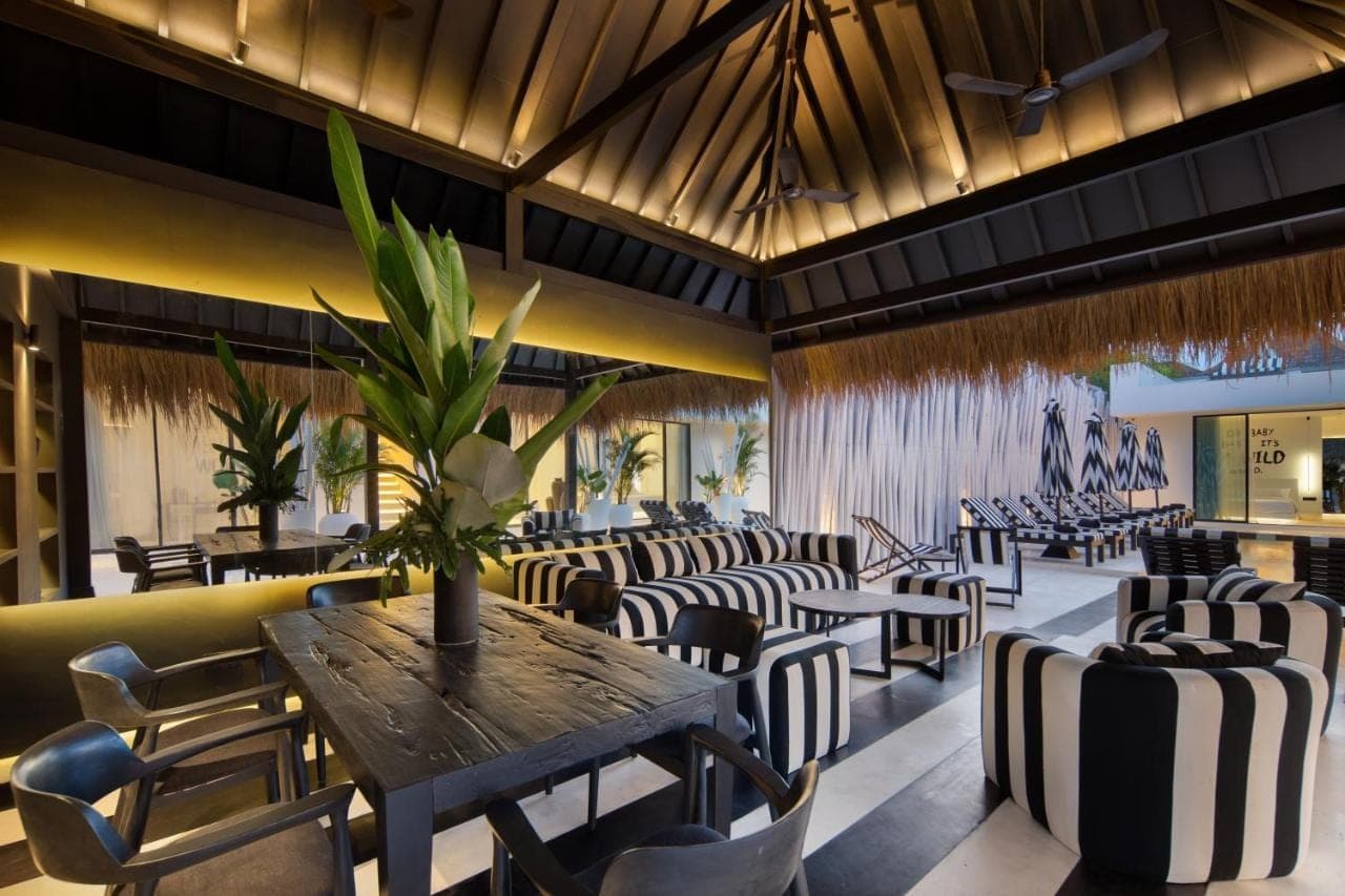 a restaurant with a wooden table and chairs at The Den Canggu in Canggu