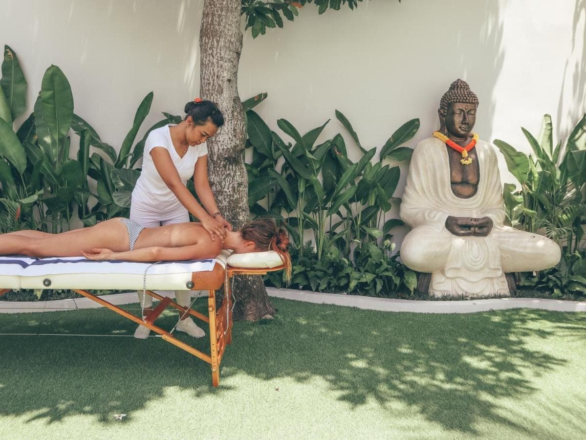 a woman sitting on a bed next to a statue at Arya Wellness - female only in Ubud