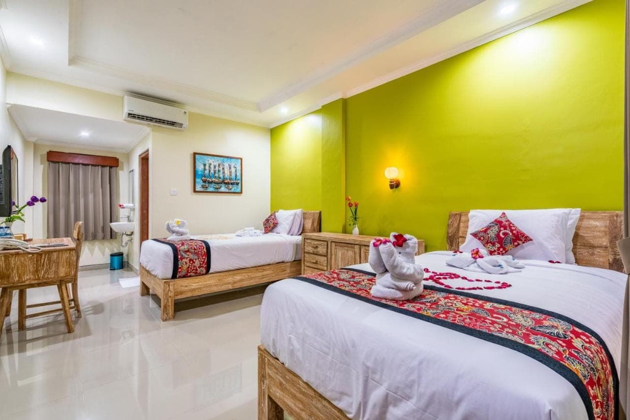 a bedroom with two beds and a yellow wall at Mejore Beach Hotel in Amed