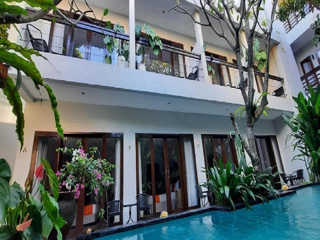 a house with a swimming pool in front of a building at The Pavilion Hotel Kuta in Kuta