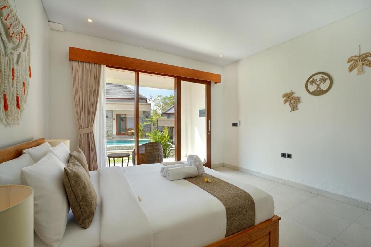 a bedroom with a large bed and a large window at Arshaka village in Uluwatu