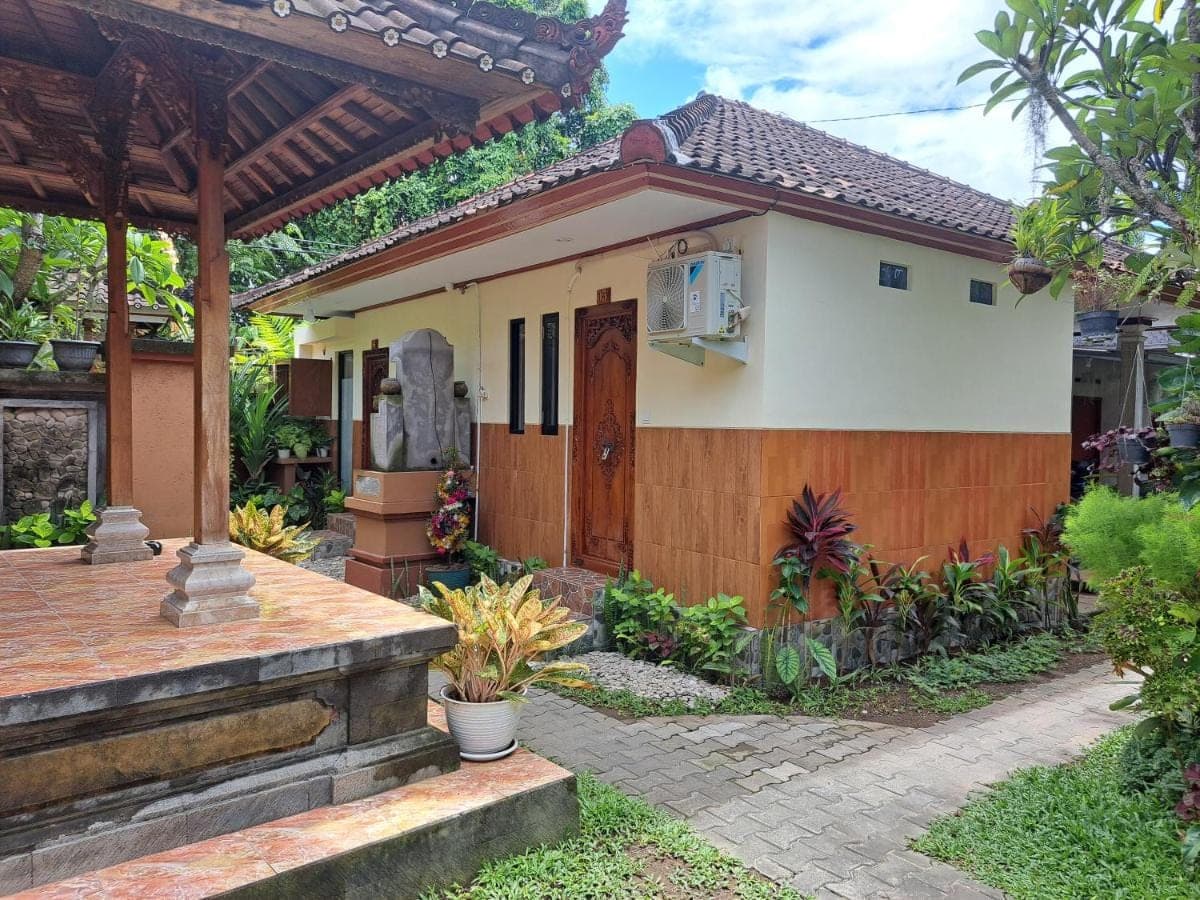 a house with a wooden door and a patio at Ascarya Guest House in Sanur