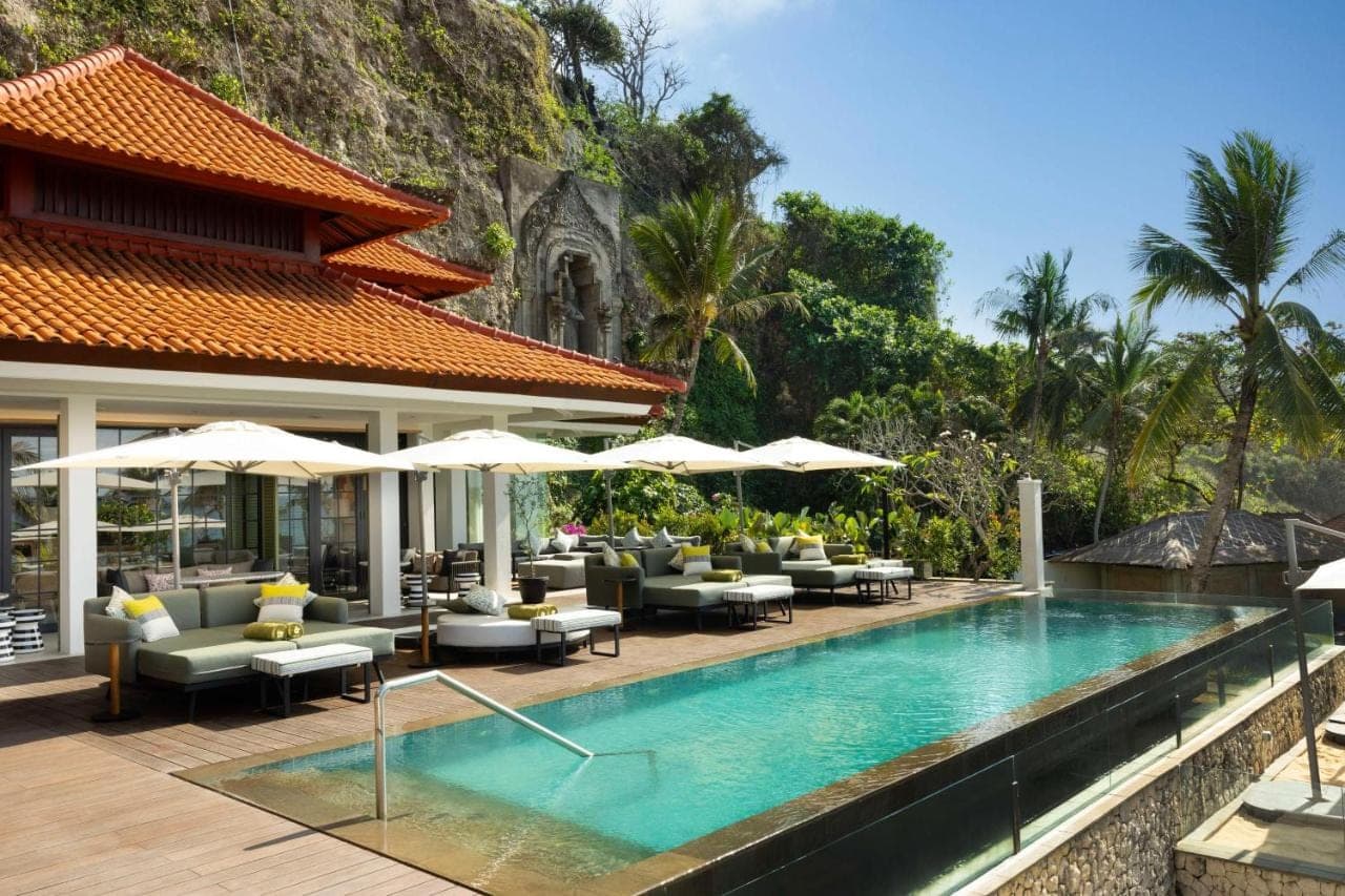 a pool at a resort with chairs and umbrellas at Hilton Bali Resort in Nusa Dua