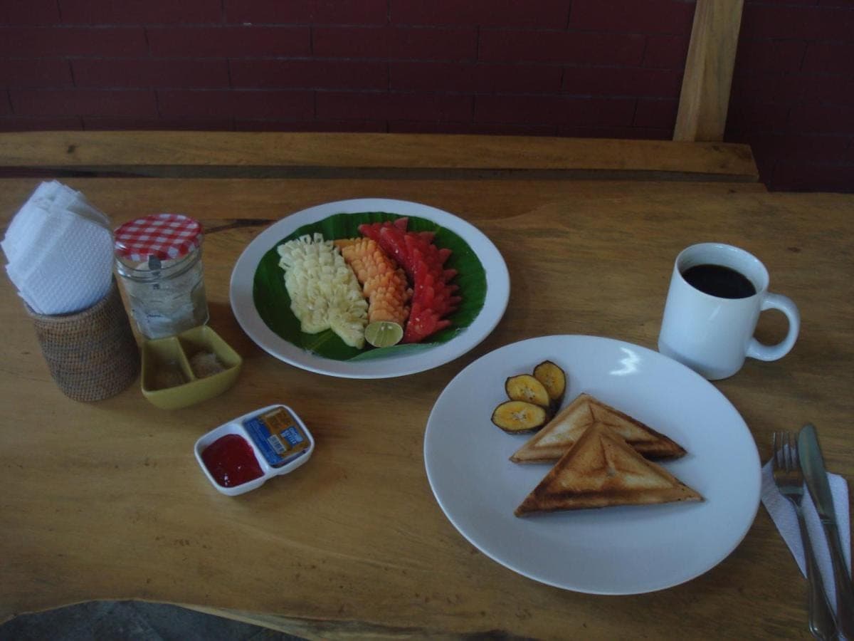 a table with two plates of food and a cup of coffee at Bulih Beach Bungalows in Amed
