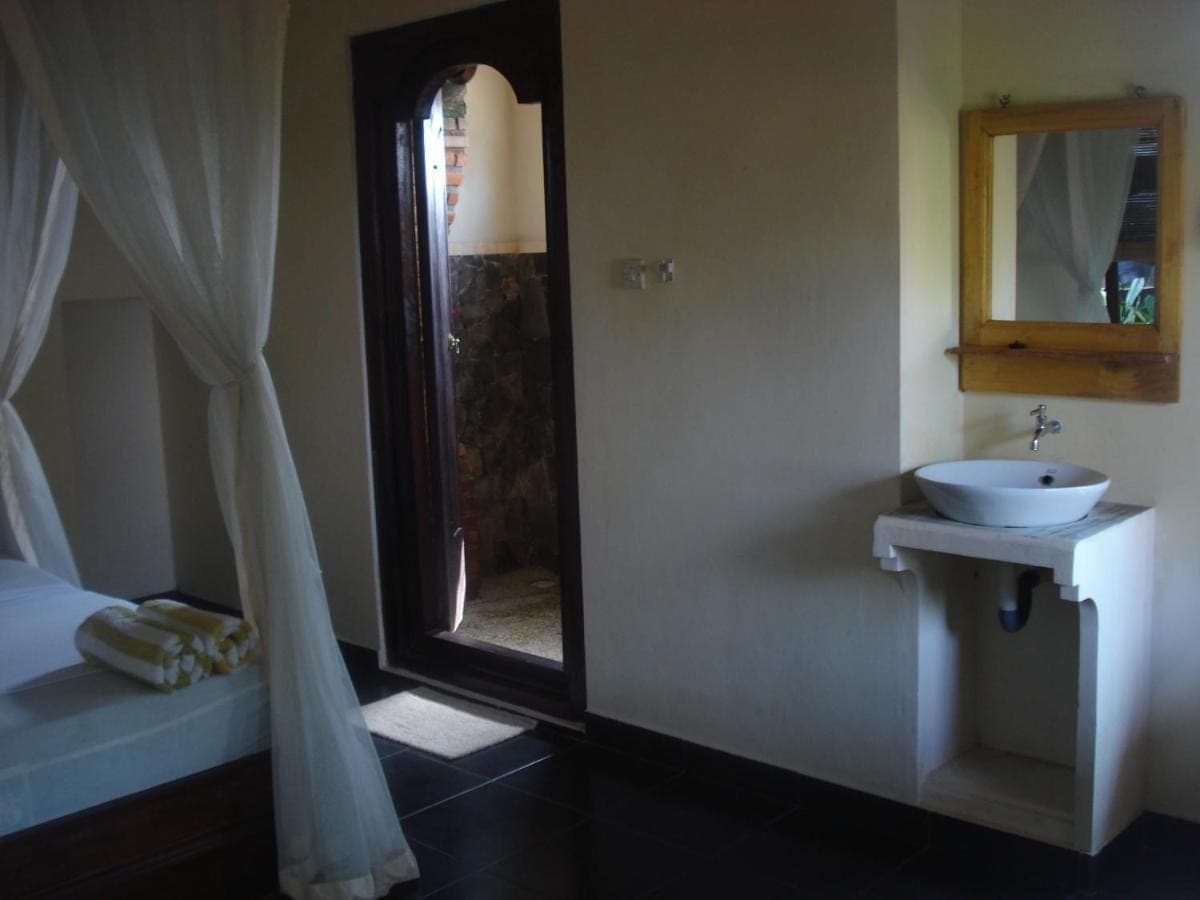 a bathroom with a sink and a mirror and a bed at Bulih Beach Bungalows in Amed
