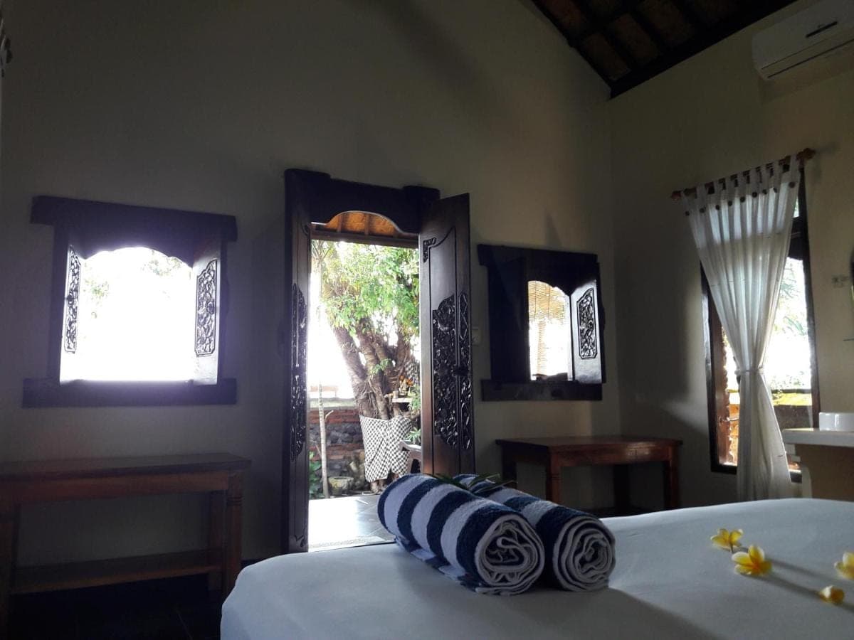 a bedroom with a bed with blue and white pillows at Bulih Beach Bungalows in Amed