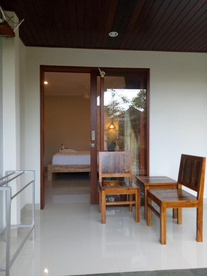 a room with a bed and a chair and a table at Wisna House in Sanur