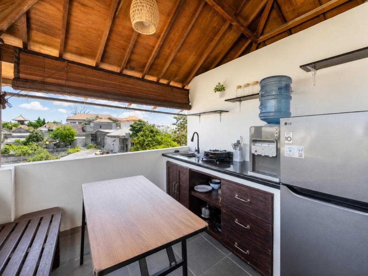 a kitchen with a wooden table and a refrigerator at Surf Bali Villa in Uluwatu