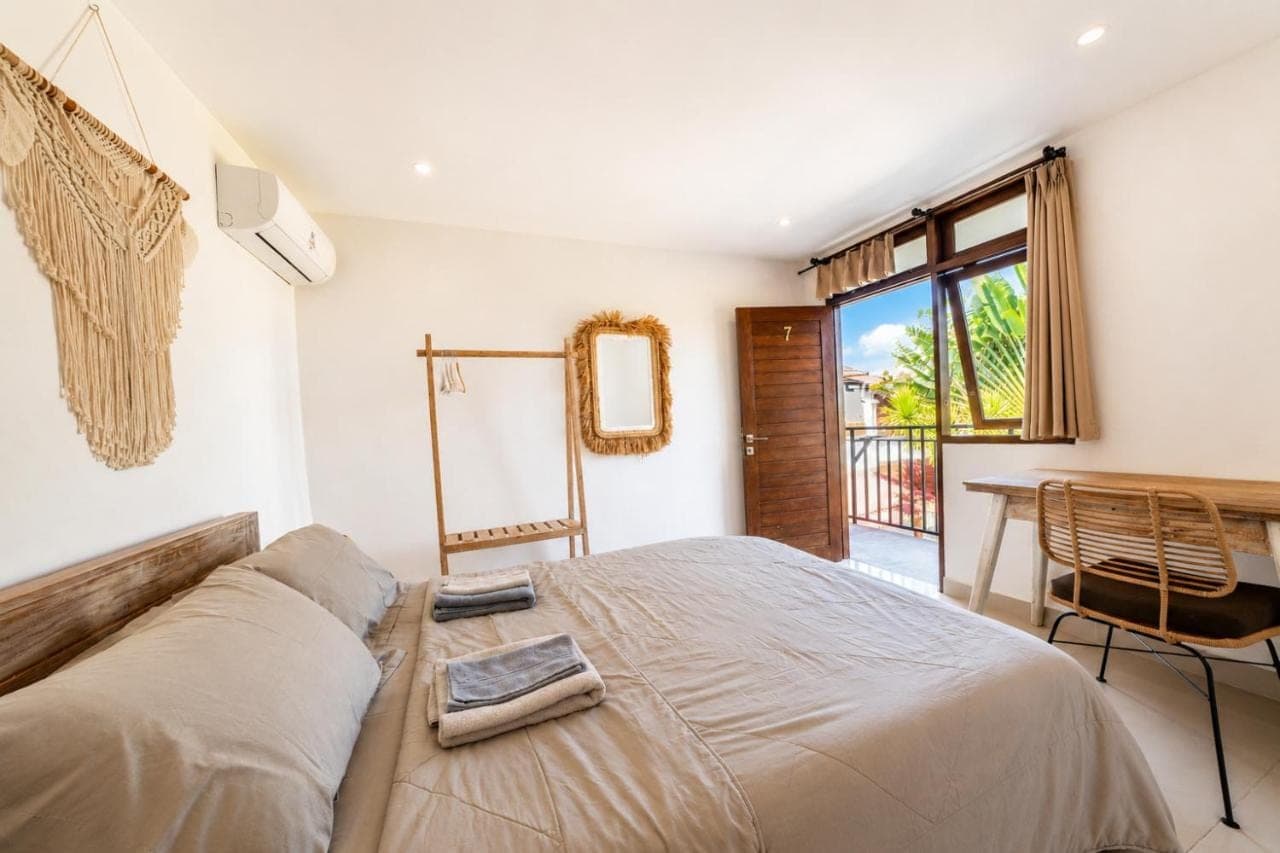 a bedroom with a bed and a table with a mirror at Surf Bali Villa in Uluwatu