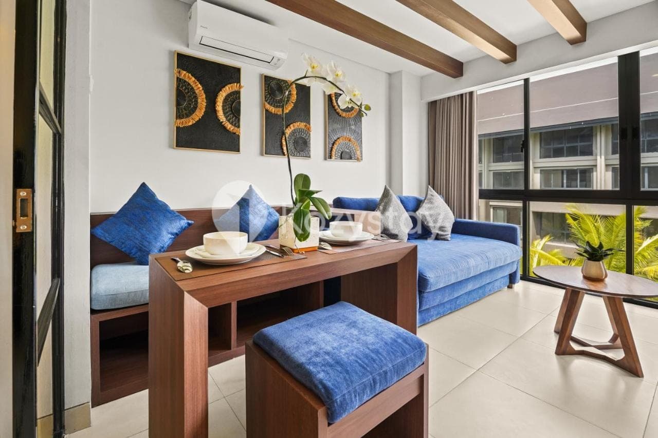 a living room with blue furniture and a table at Vantara by Kozystay - Nusa Dua in Nusa Dua