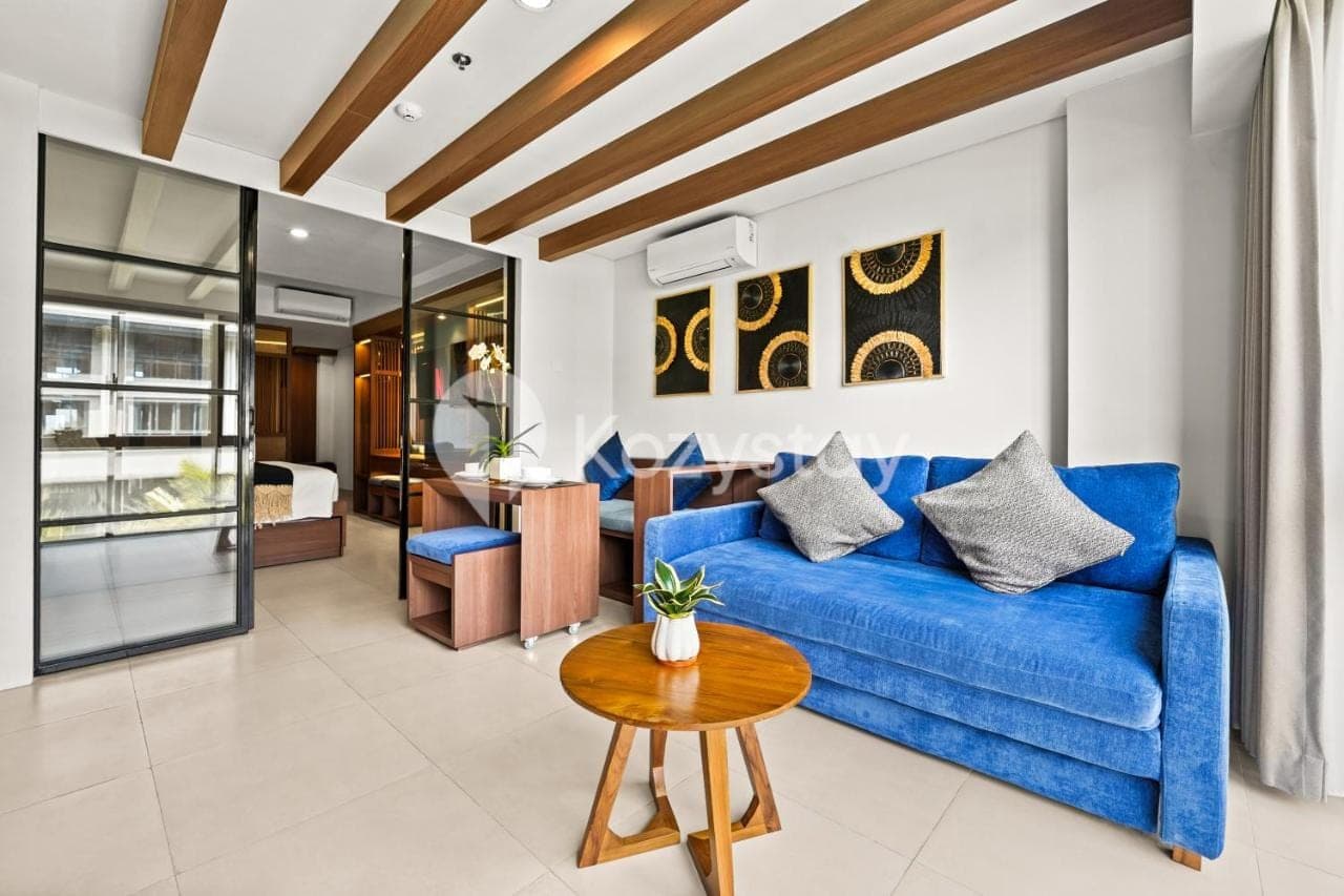 a living room with a blue couch and a table at Vantara by Kozystay - Nusa Dua in Nusa Dua