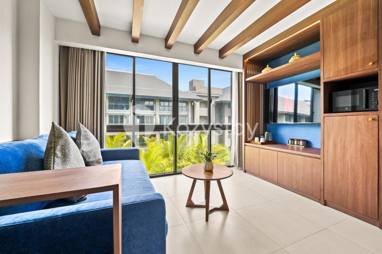 a living room with a blue couch and a table at Vantara by Kozystay - Nusa Dua in Nusa Dua
