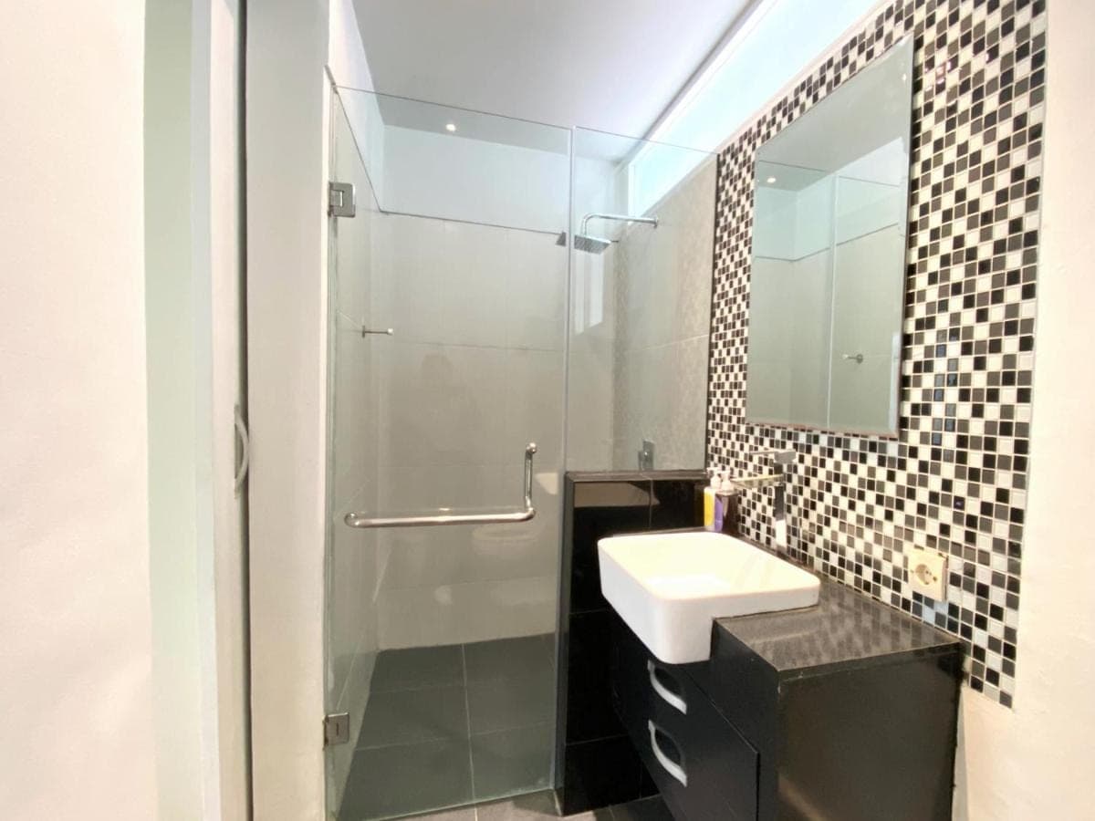a bathroom with a sink and a shower with a mirror at Coast Boutique Hotel in Kuta