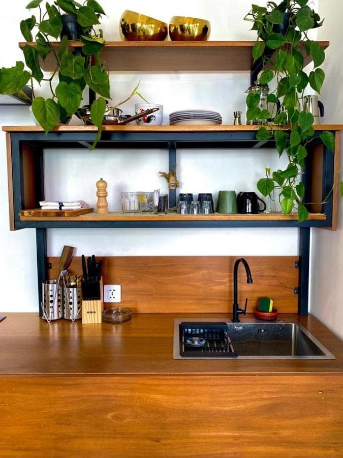 a kitchen counter with a sink and lots of plants at Tirta Loft in Canggu