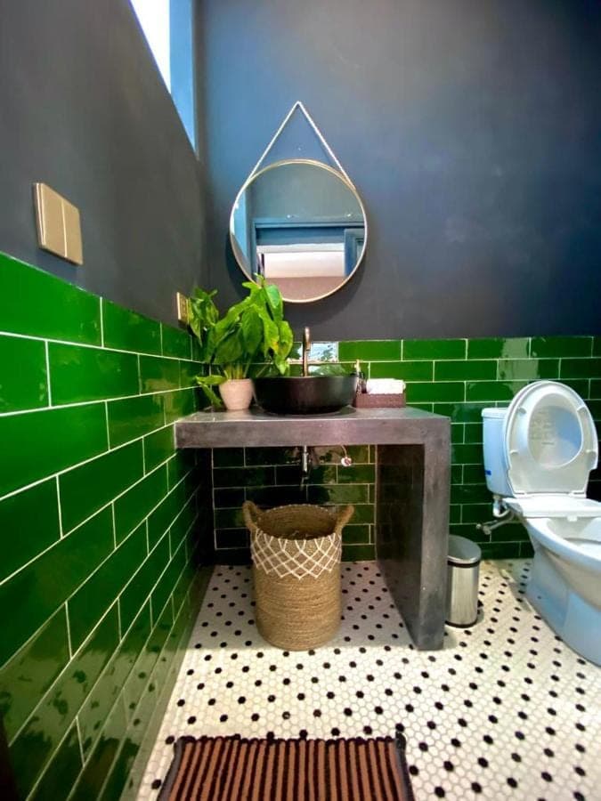 a green tiled bathroom with a sink and a toilet at Tirta Loft in Canggu