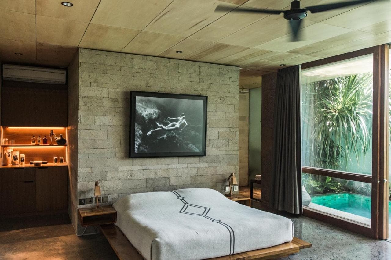 a bedroom with a bed and a tv on a brick wall at The Slow Canggu in Canggu
