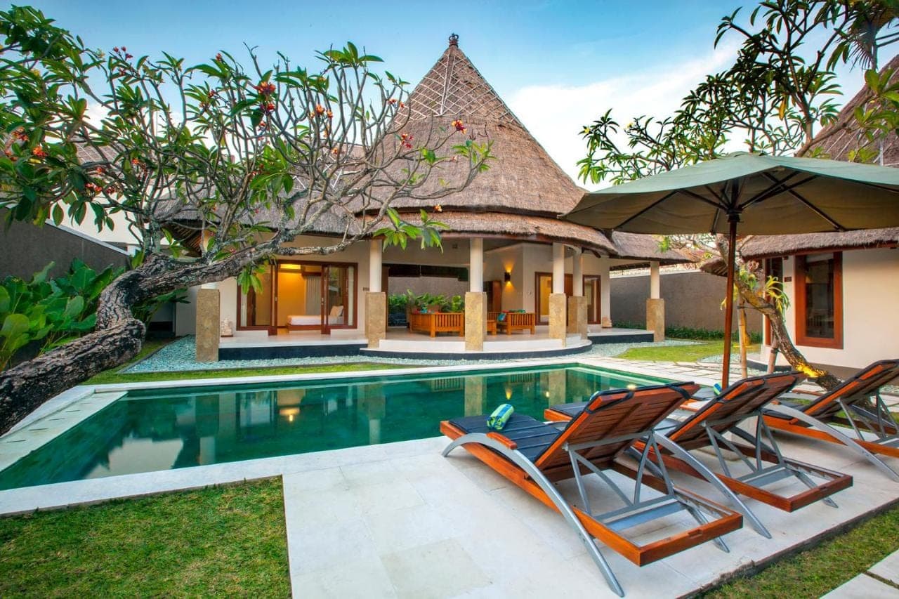 an image of a swimming pool with two chairs and an umbrella at Mutiara Bali Boutique Resort &amp; Villa in Seminyak