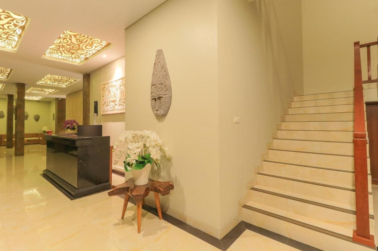 a lobby with stairs and a vase of flowers on a chair at Linda Villa 2 in Sanur