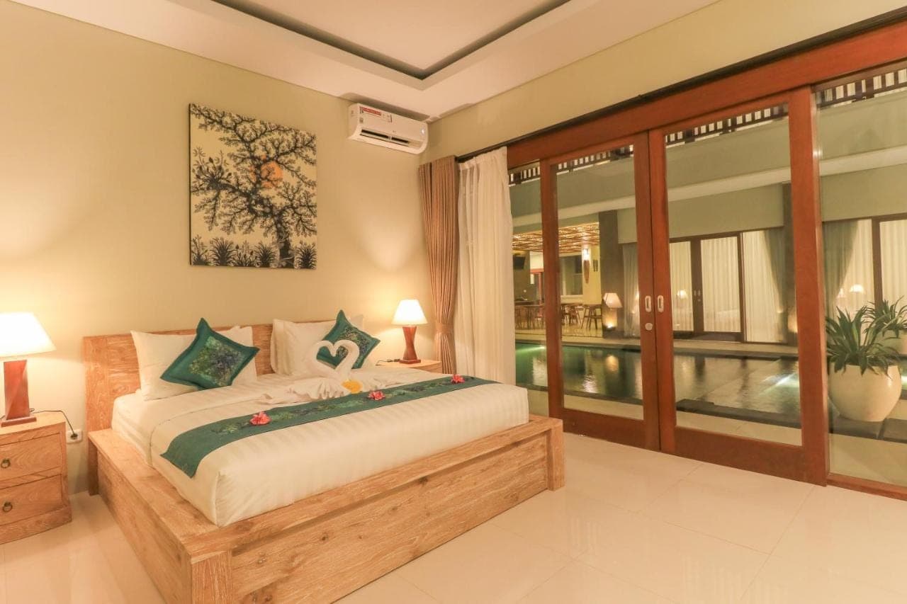 a bedroom with a large bed and a balcony at Linda Villa 2 in Sanur
